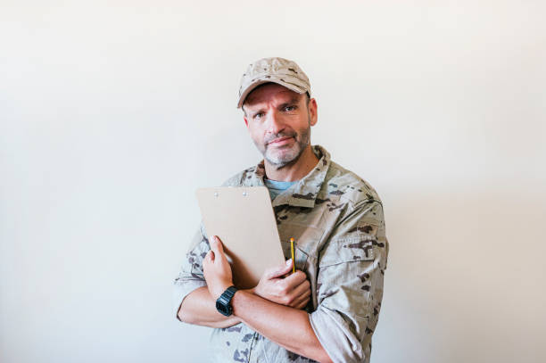 istock Caucasian man in camouflaged military uniform holding notebook. 1475817780