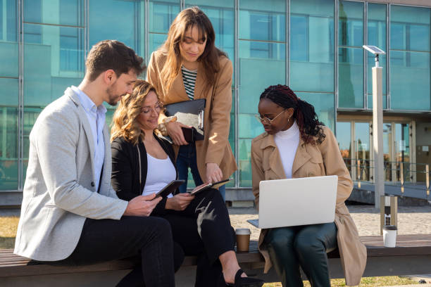 Business colleagues using laptop outside of office building stock photo