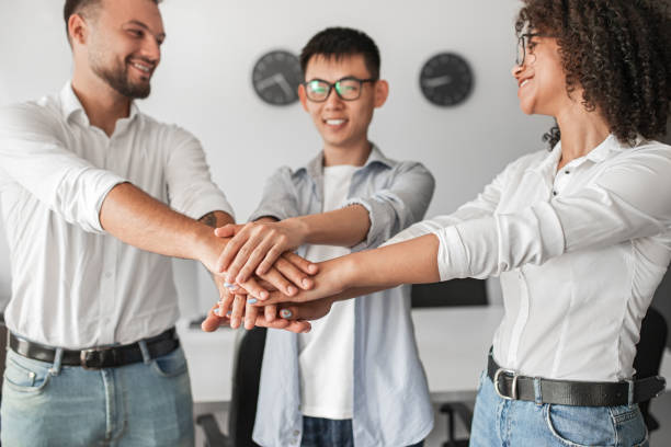 istock Positive diverse team stacking hands together in office 1475823016
