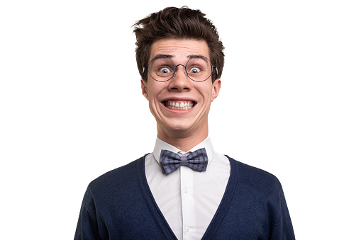Goofy young man in smart casual clothes and glasses looking at camera with crazy smile against white background