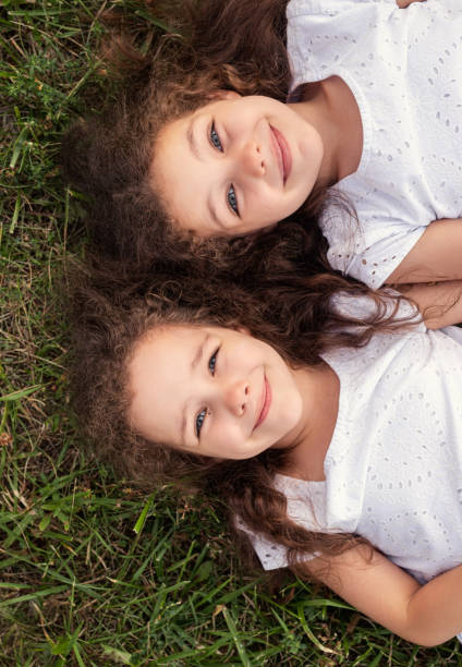 istock Twins lying on grass in park 1475825410