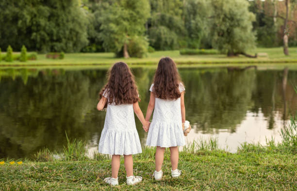 istock Anonymous sisters standing near lake 1475825424