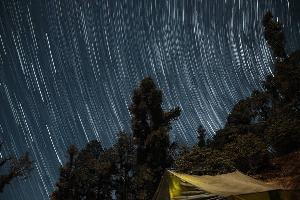 Star trails with a lit up camp