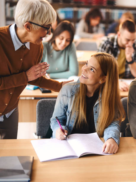 istock Happy senior professor assisting her student on a class in the classroom. 1475829704