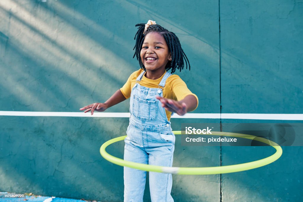 Happy, playing and portrait of a child with a hula hoop for fitness, practice and hobby. Smile, carefree and an African girl with a toy for happiness, playtime and break on a school playground Child Stock Photo