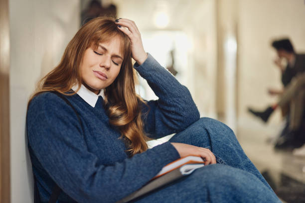 istock High school female student sitting on a floor alone during a break in a hallway. 1475830509