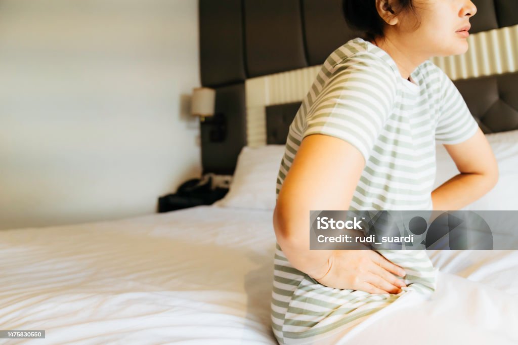These cramps are getting worse now Closeup shot of a woman suffering with stomach cramps at home Abdomen Stock Photo