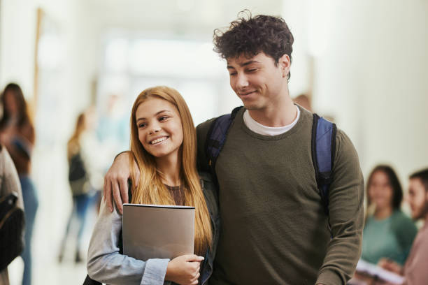 istock Happy college couple walking embraced in a hallway. 1475831519