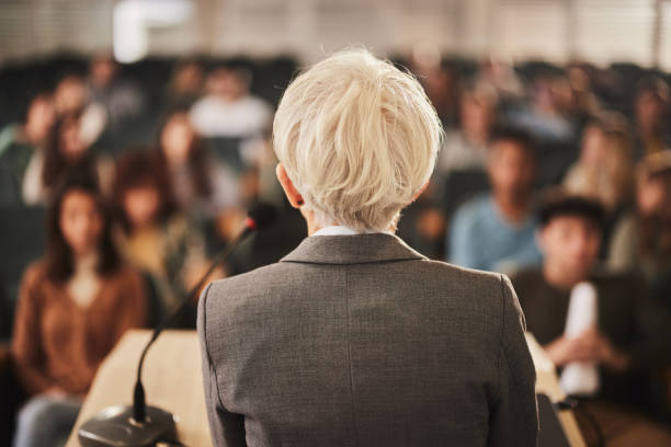 istock Back view of a female professor teaching her students at lecture hall. 1475831653