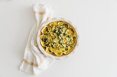 Quiche. Healthy homemade chicken pie with broccoli and spinach on white wooden table