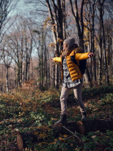istock Happy female hiker walking on tree trunk in autumn day. 1475835748