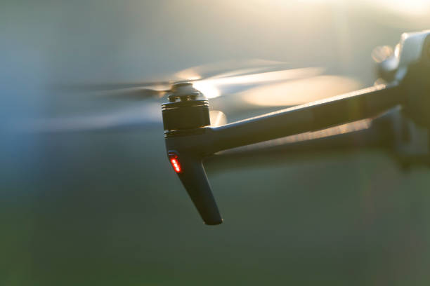 Drone aircraft with blurred fast rotating propellers and video camera flying in air.