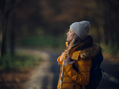 Profile view of a female backpacker enjoying in the sunlight with her eyes closed in nature. Copy space. Photographed in medium format.