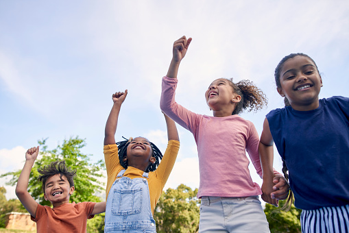 Children, energy and diversity with friends cheering together outdoor while having fun during the day. Kids, freedom or celebration with a girl and boy group playing or bonding outside in summer