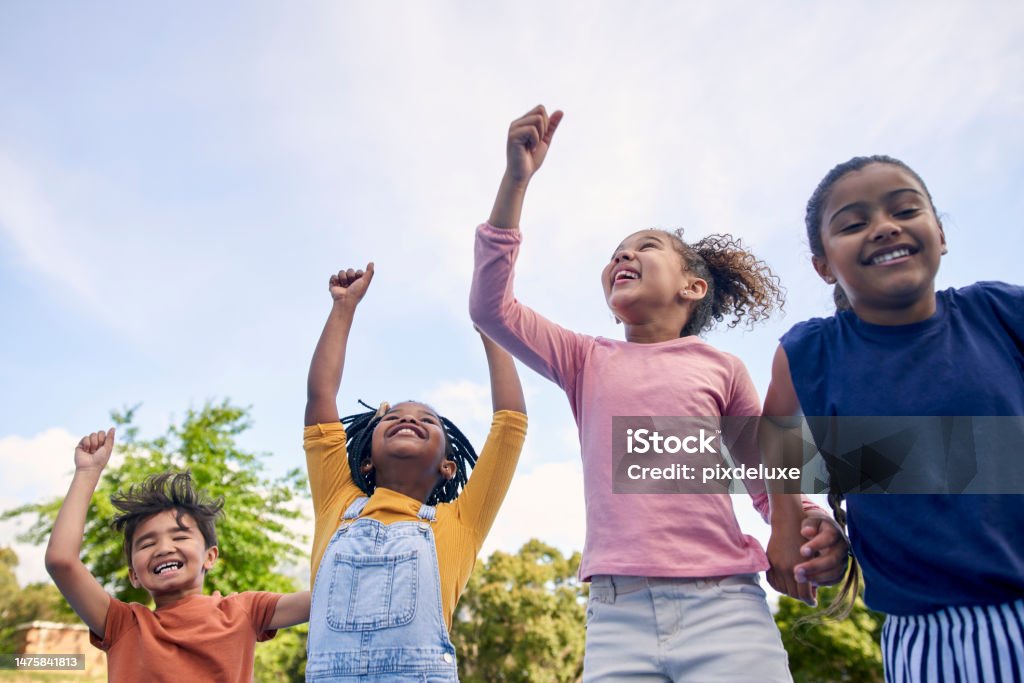 Children, energy and diversity with friends cheering together outdoor while having fun during the day. Kids, freedom or celebration with a girl and boy group playing or bonding outside in summer Child Stock Photo