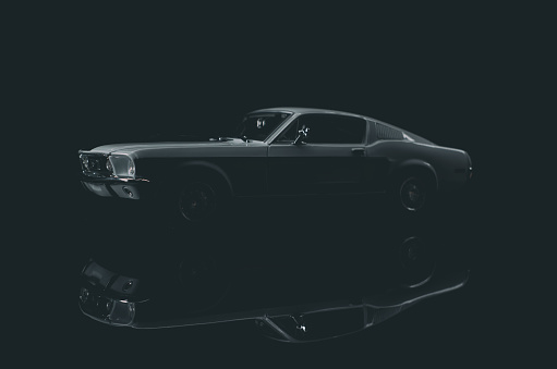 Beaconsfield, UK - March 24, 2023: A scale model of 1968 Ford Mustang, a genuine icon of the 1960's, sitting on a reflective black surface against a black background.