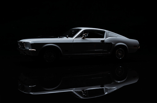 Beaconsfield, UK - March 22, 2023: A scale model of 1968 Ford Mustang, a genuine icon of the 1960's, sitting on a reflective black surface against a black background.