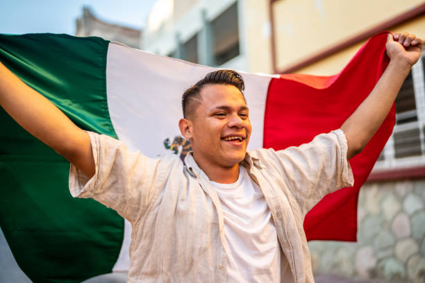 istock Young man walking while holding a mexican flag in the street 1475843616