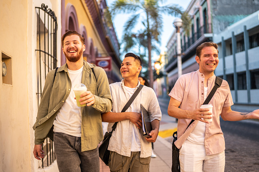 Young friends men talking while walking through the city