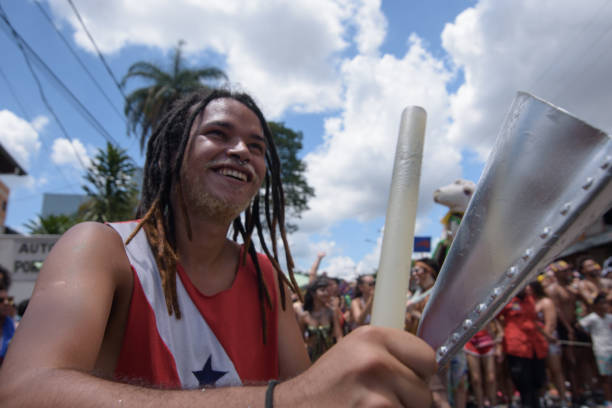 Young man playing “cowbell" musical instrument.