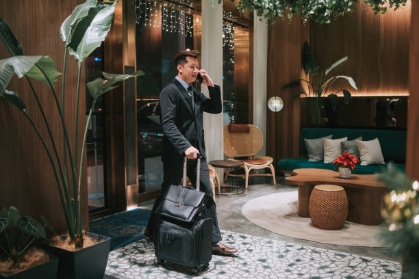 istock Asian businessman walking into hotel checking in while talking on the phone 1475850921
