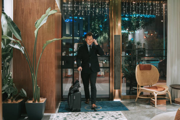 istock Asian businessman walking into hotel checking in while talking on the phone 1475851131