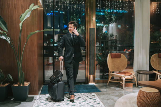 istock Asian businessman walking into hotel checking in while talking on the phone 1475851226