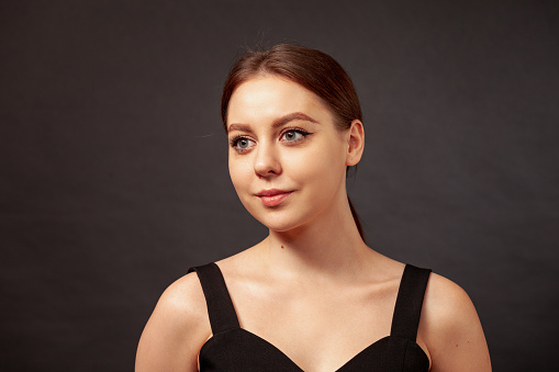 Close-up studio portrait of an attractive young white woman with brown hair against a black background