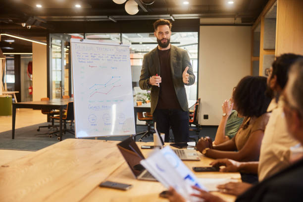 istock Young businessman talking during a whiteboard presentation for coworkers 1475863048