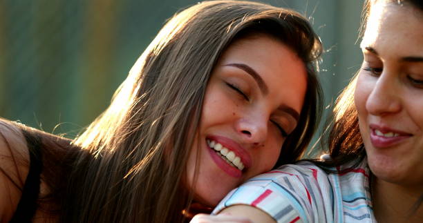 Woman real life smile leaning on friend shoulder stock photo