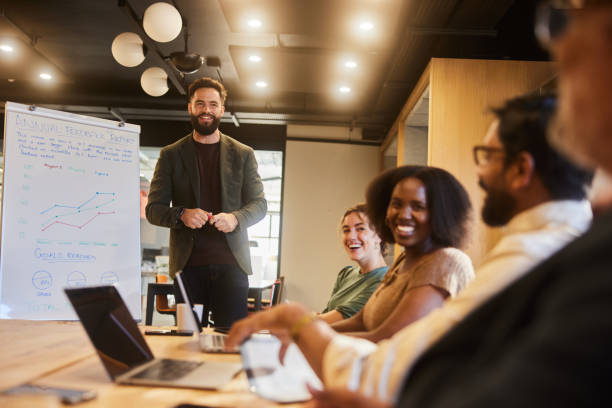istock Smiling businessman giving diverse colleagues a whiteboard presentation in an office 1475863938