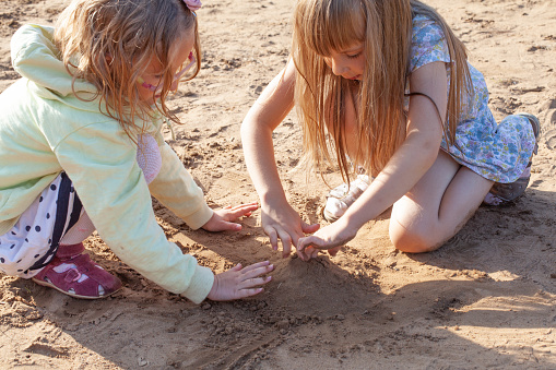 Two child girls are playing with sand