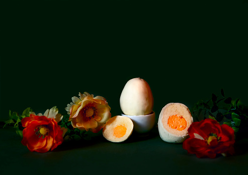 The Art of Dessert in Confectionery. The Best Alternative to Easter Cakes. Dessert in the Form of an EGG, protein from biscuit crumbs, yolk from mousse cream. Postcard. Dessert on a Dark Background