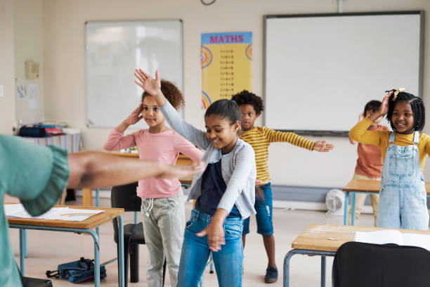 istock Teacher, classroom and children dancing in fun group activity for learning, education or childhood development at school. Little students moving dance in class for team exercise or listening skills 1475870216