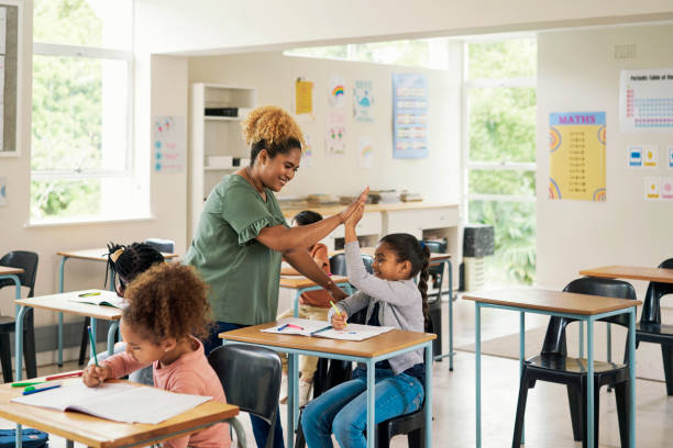 istock Education, high five and teacher with girl in classroom for learning, support and motivation. Study, assessment and development with student and woman in school for celebration, exam and result 1475870321