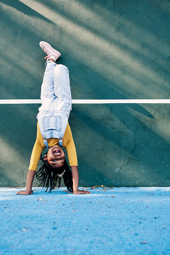 Portrait, handstand and mockup with a black girl playing outdoor alone during recess at school. Kids, upside down and game with a female child joking or having fun outside on a playground or court