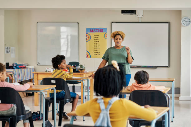 istock Classroom, teacher and students in discussion about exam in a lecture hall for knowledge development. Learning explanation, student help and school employee in test study lesson with children 1475870449