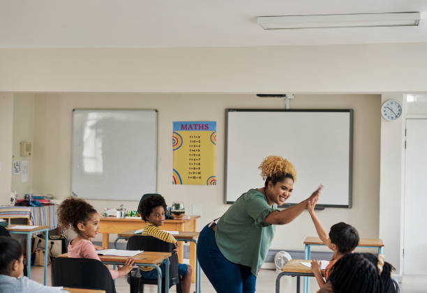 istock Education, classroom and teacher high five student for motivation during a lesson in school. Happy, celebration and female educator celebrating with the children for knowledge or learning at academy. 1475870466