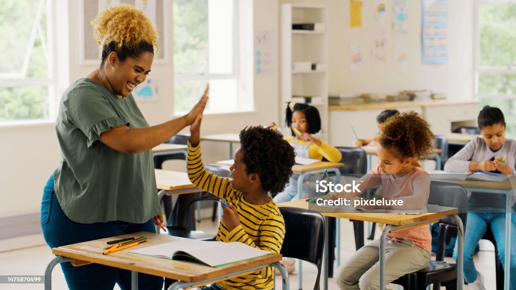 Education, high five and teacher with children in classroom for learning, support and motivation. Study, assessment and development with student and woman in school for celebration, exam and result Teacher Stock Photo