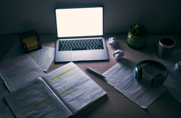 Laptop, mockup and desk for studying at night in student dormitory, dark room and technology. Background of computer, blank screen and notes on table in evening for education, learning and internet