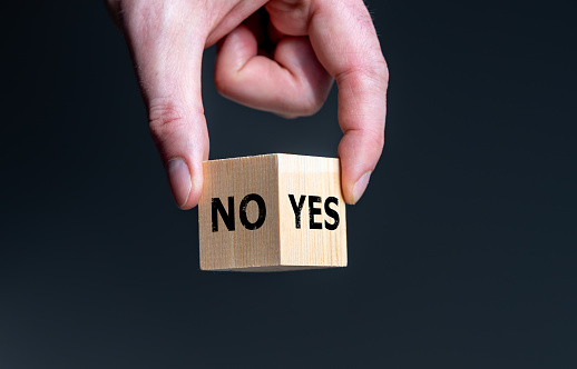 Symbol for the decision between yes and no. Wooden cube with the words 'yes' and 'no'.