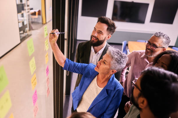 istock Mature businesswoman and colleagues having a brainstorming session using adhesive notes 1475875941