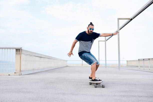 istock Stylish man in sunglasses skating perfectly on longboard. 1475877362