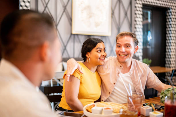 istock Couple embracing while talking with their friends on a restaurant 1475879062
