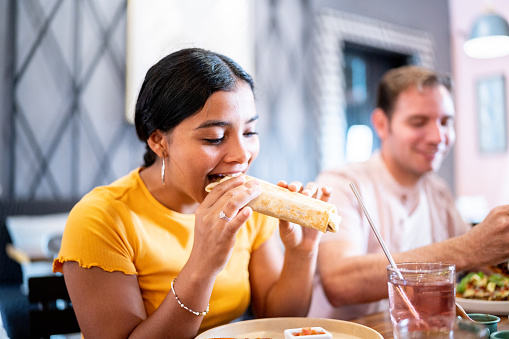 Young woman eating a burrito on a restaurant