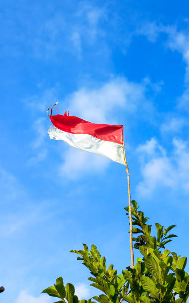 istock Vertical image of beautiful Indonesian flag on blue sky background 1475879687