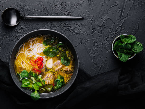 istock Chicken soup with vegetables in black bowl with red pepper 1475881648