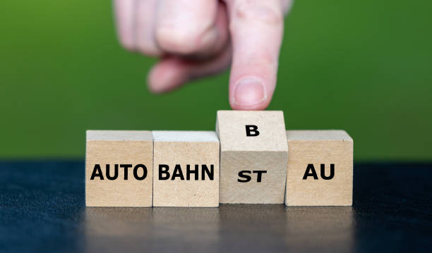 istock Hand turns cube and changes the German expression 'Autobahnstau' (traffic jam on the freeway) to 'Autobahnbau' (construction of freeway). 1475884820