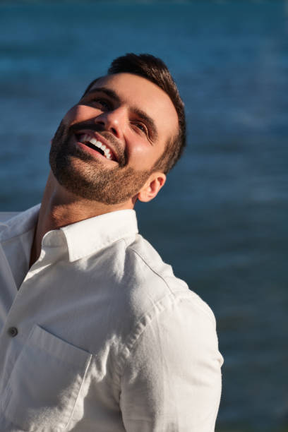 istock Cheerful young ethnic guy smiling near sea in sunlight 1475885278