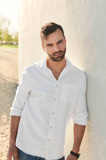 istock Stylish young ethnic male leaning on wall and looking at camera 1475885308